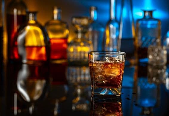 Whiskey with ice on a black table in a bar.