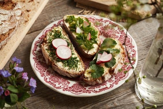 Edible plants - chives, garlic mustard, and gooseberries on buttered sourdough slices.