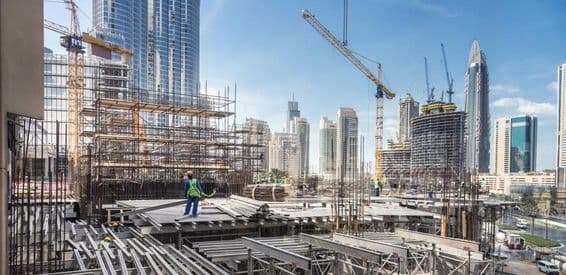 Construction in Dubai, a worker stacking wooden planks.