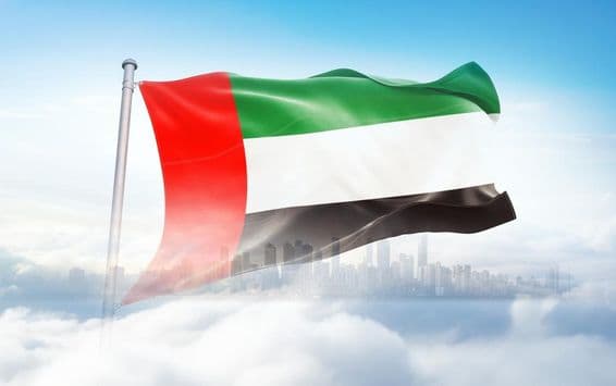 UAE flag waving in the clouds, skyscrapers in the background.