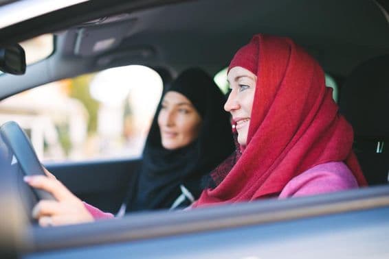 Muslim woman driving a car, transporting another Muslim woman.