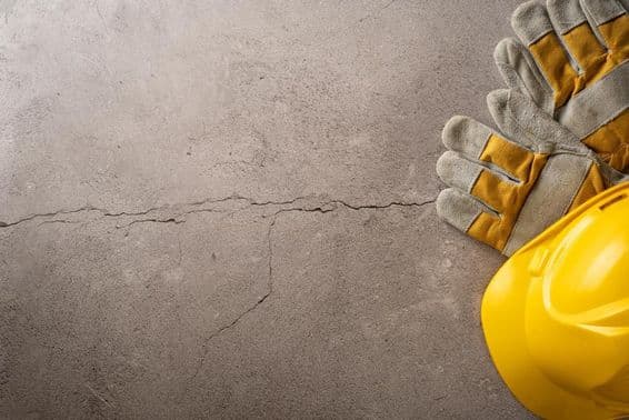 Break time, yellow helmet and work gloves placed on a cracked concrete surface.