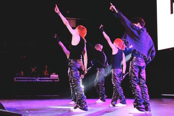 K-Pop band dancing on stage.