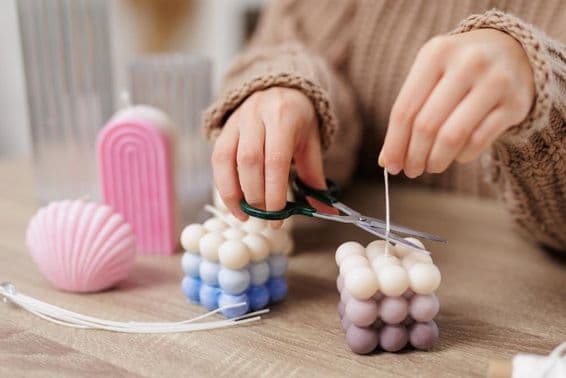 Bauble candle on a table, little girl cuts the wick.