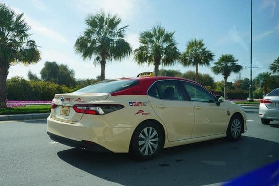 Dubai taxi with red roof driving on the road.