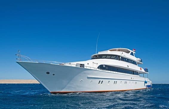 A large luxury private motor yacht cruising on the tropical sea.