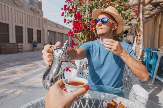 A man in Dubai resting in an Arab café, pouring aromatic coffee from a dallah coffee pot.