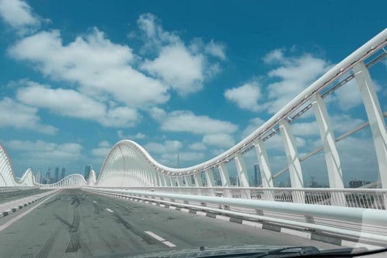 White modern abstract bridge with blue sky and clouds in the background.