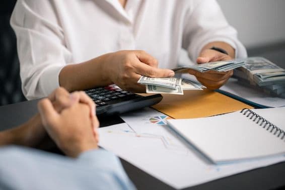 A person wisely managing finances, saving cash from their salary, ensuring stable income for future payments and business investments.