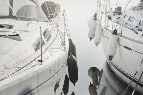 White, modern sailboat docked at a marina.