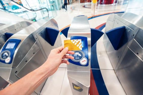 A male passenger uses a golden NOL card at the Dubai metro to pass through a turnstile and travel in the first coach.