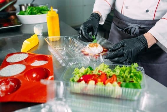 The chef prepares food in the restaurant and packs it in disposable containers.