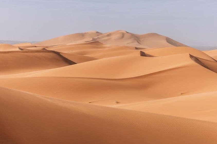 Towering dunes, golden sunset over a calm, quiet landscape.