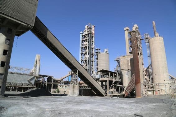 Cement factory with towers and conveyor belt.