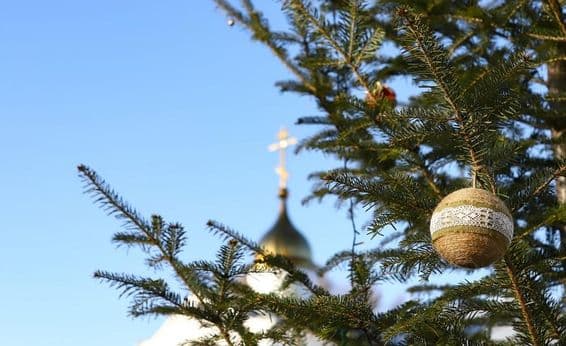 Branch of a Christmas tree with ornaments, with an Orthodox cross in the background