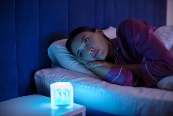 Sad sleepless woman lying in bed, staring away, unable to sleep, suffering from insomnia.