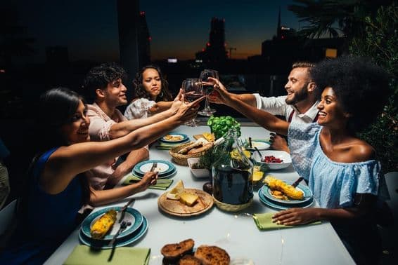 Group of friends enjoying a meal and celebrating on a beautiful penthouse balcony.
