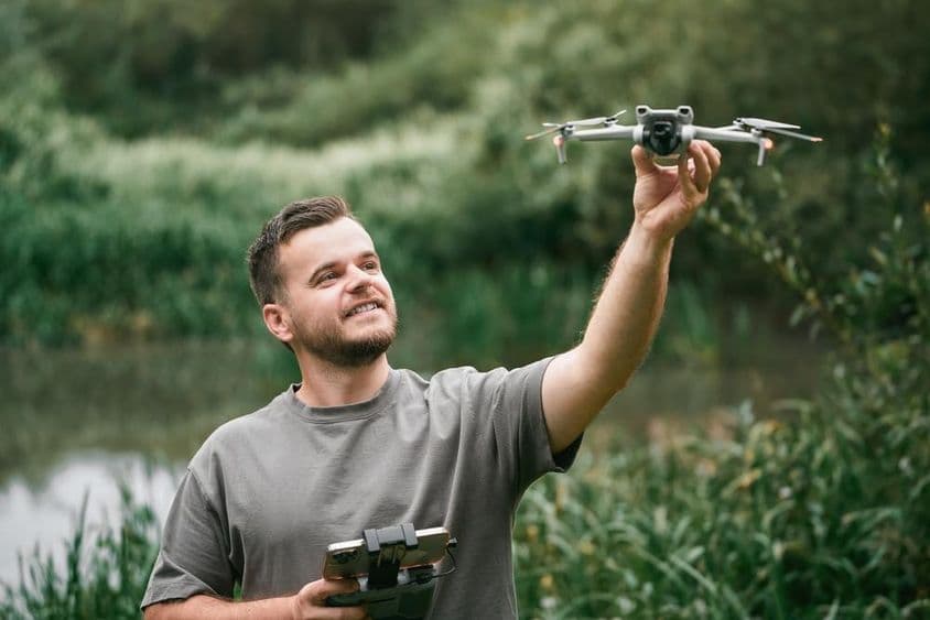 Drone instructor with drone in hand during outdoor class.