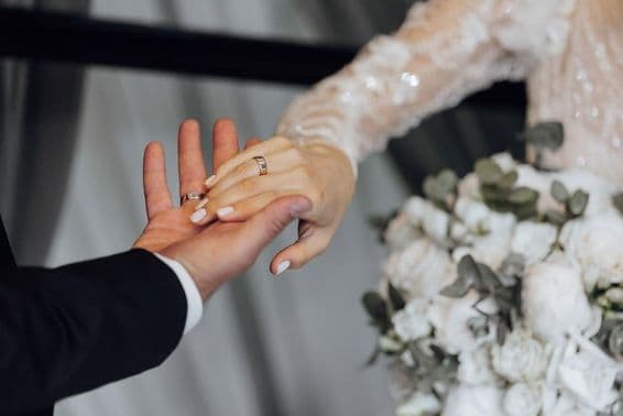 Bride and groom holding hands, bride wearing a white dress.