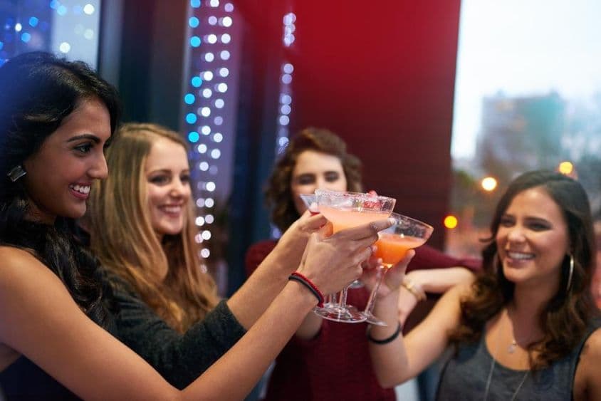 Girls toasting with drinks in a cocktail bar.