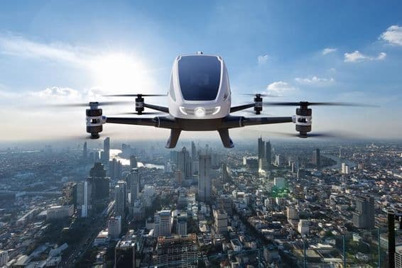Autonomous driverless aerial vehicle flying against a city backdrop.