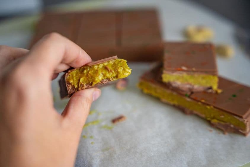 Piece of Dubai chocolate with pistachio and kataifi pastry in a woman's hand.