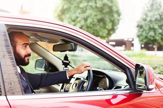 Young businessman driving a red rental car.