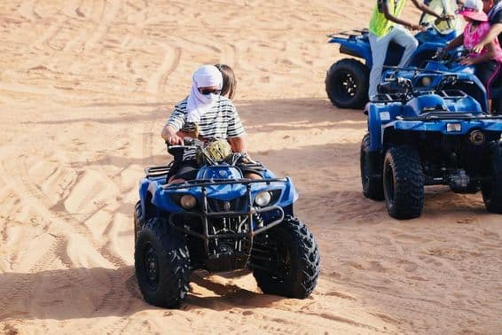 Young couple riding a squad in Dubai desert.