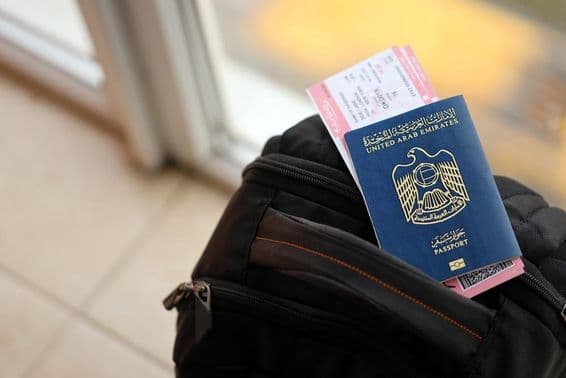 Blue United Arab Emirates passport with flight tickets on a backpack close-up.