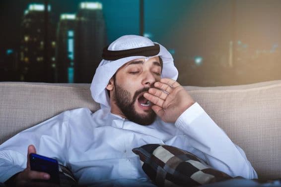 Arab man yawning while watching television.