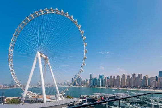 Ain Dubai Ferris wheel with skyscrapers and sea in the background.