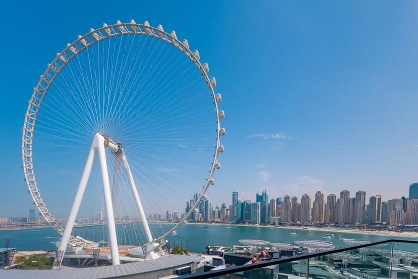 Ain Dubai Ferris wheel with skyscrapers and sea in the background.