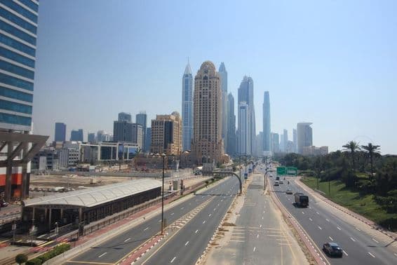 Dubai street view with skyscrapers and tram in background.
