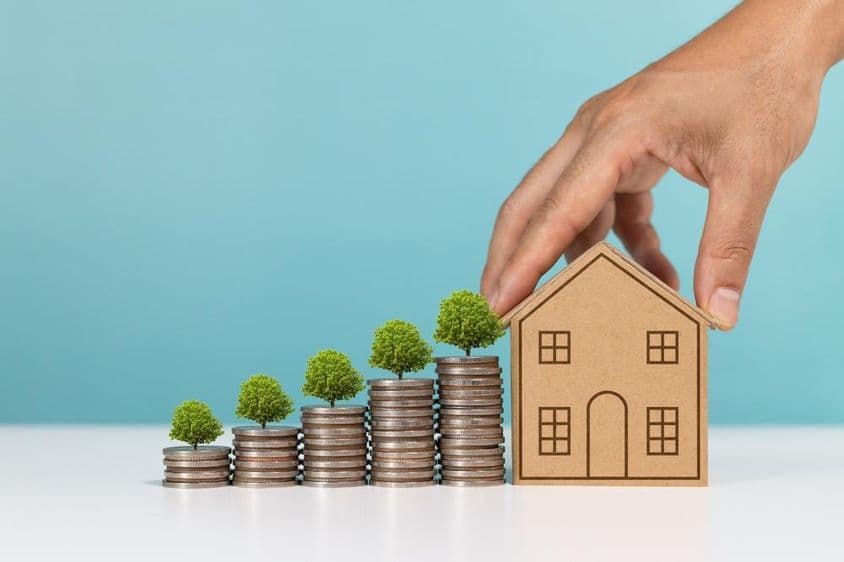 Coins topped with growing tree, indicating real estate investment growth.