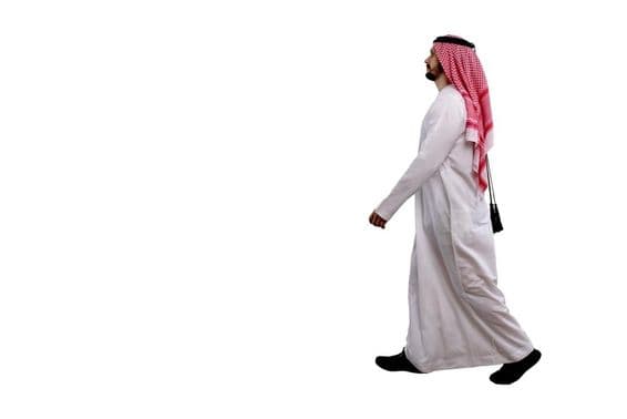 Arab man walking in traditional attire.