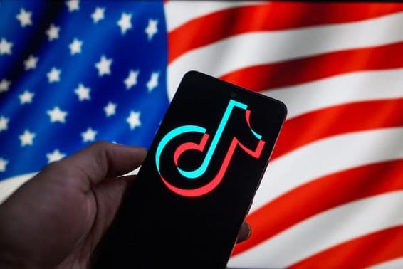 The TikTok logo displayed on a smartphone with the USA flag in the background.