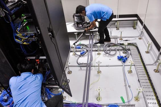 Workers building a server room, raised floor and rack cabinets.