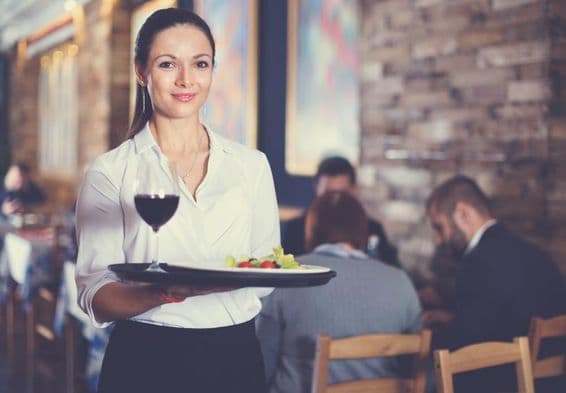 Happy waitress holding a serving tray for restaurant guests.