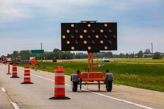Flashing orange lights with arrows and road cones guiding drivers during lane closures.