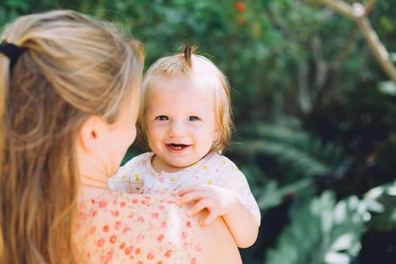 A happy young mother holding her daughter in the park.