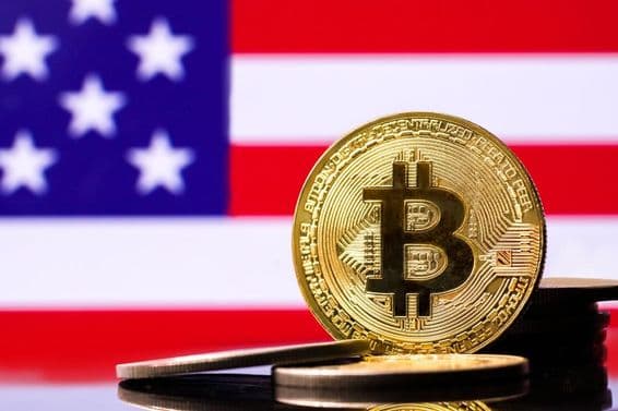 Gold Bitcoin metal coin with the USA flag in the background.