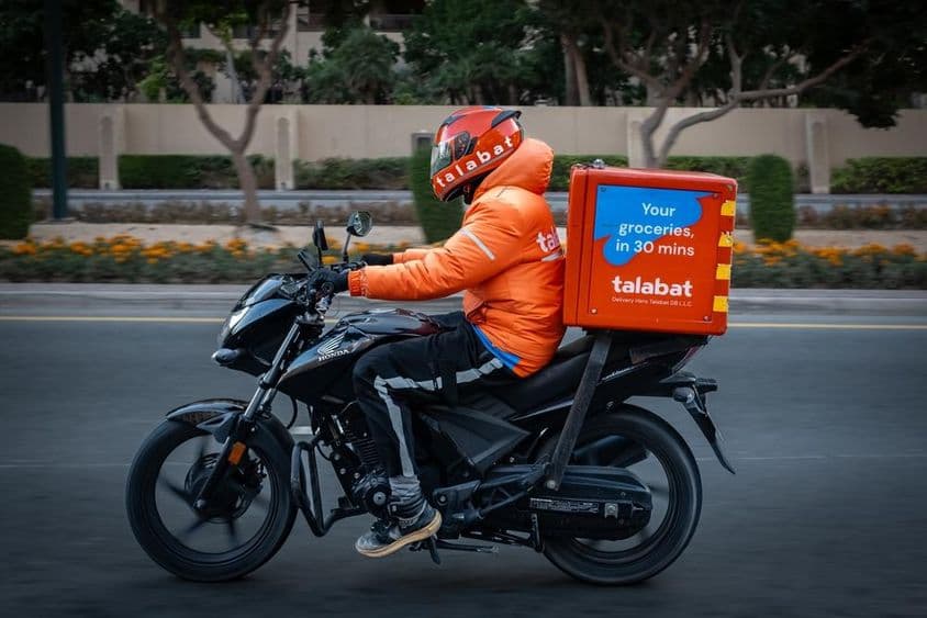 Motorcyclist delivering food, Talabat courier on a Dubai road.