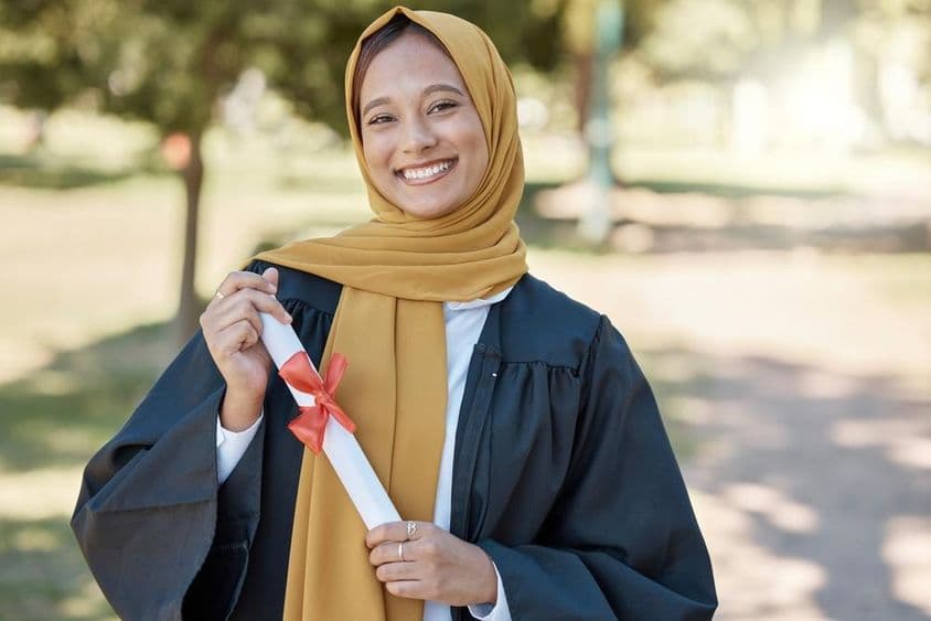 Islamic student with a diploma at an outdoor university.