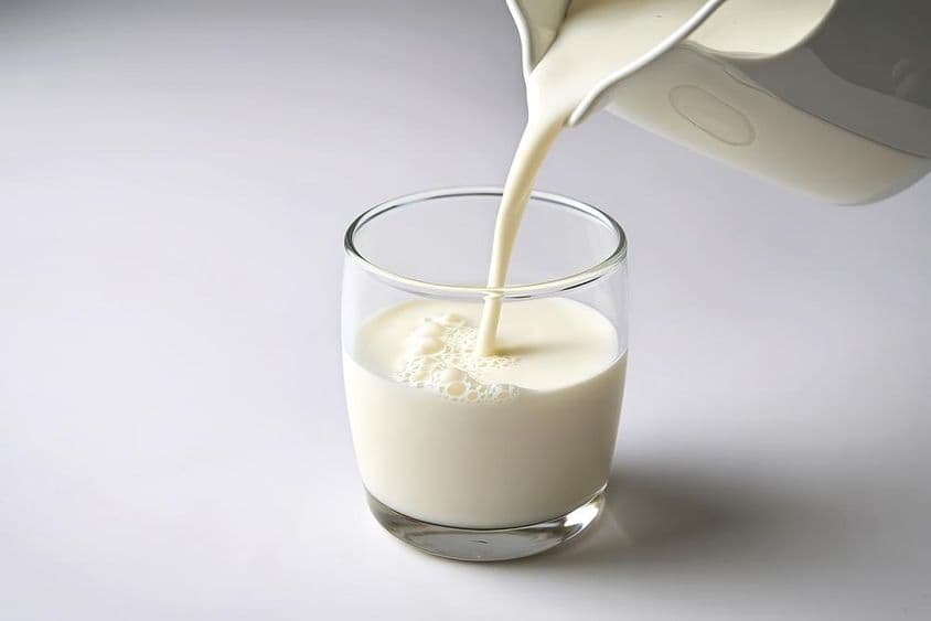 Pouring milk into a small glass.