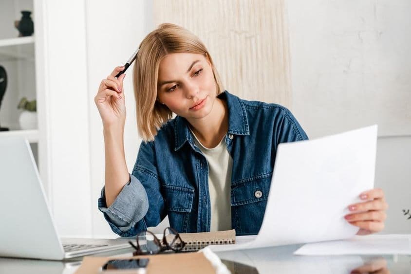 Pondering freelancer preparing taxes on a laptop.