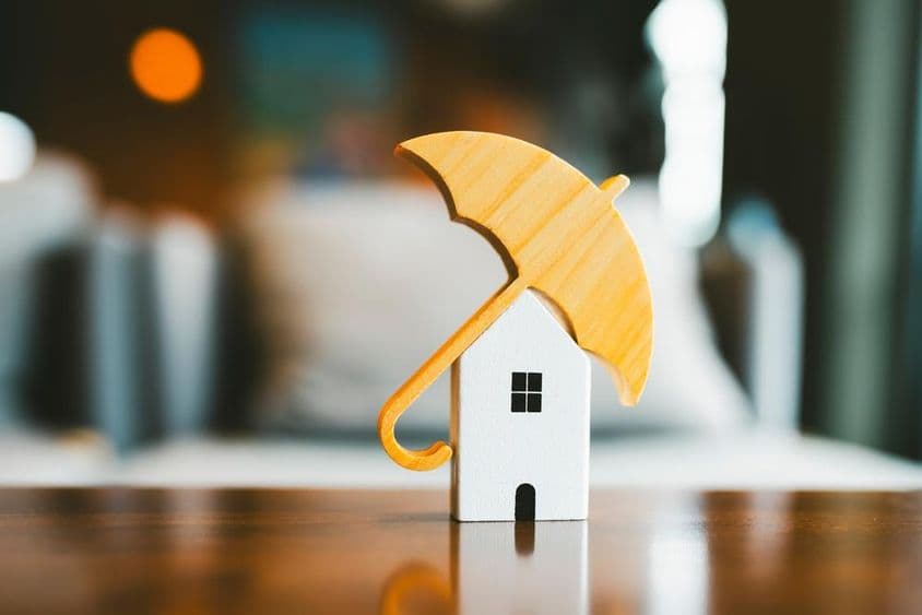Model umbrella on a wooden house, home insurance.