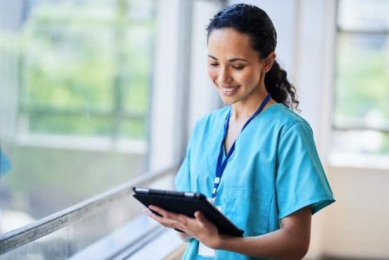 Smiling nurse with a digital tablet in a modern medical facility.
