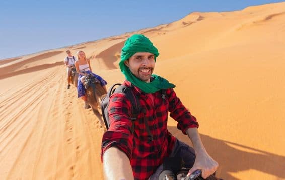 A person enjoying a group outing while riding a camel in the desert.