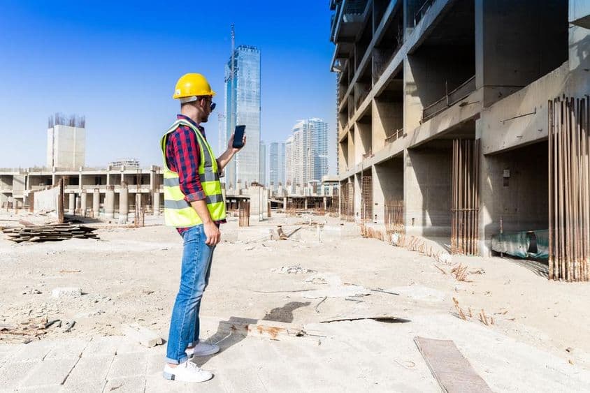 Smartphone, hard hat, and hi-vis jacket under the Dubai skyline, construction worker.