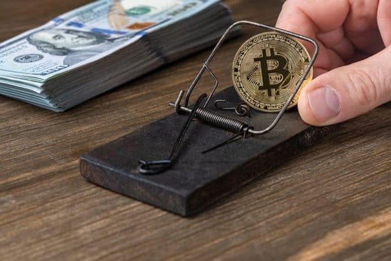 Cryptocurrency coins Bitcoin in mouse trap, trapped with 100 US dollar bills.